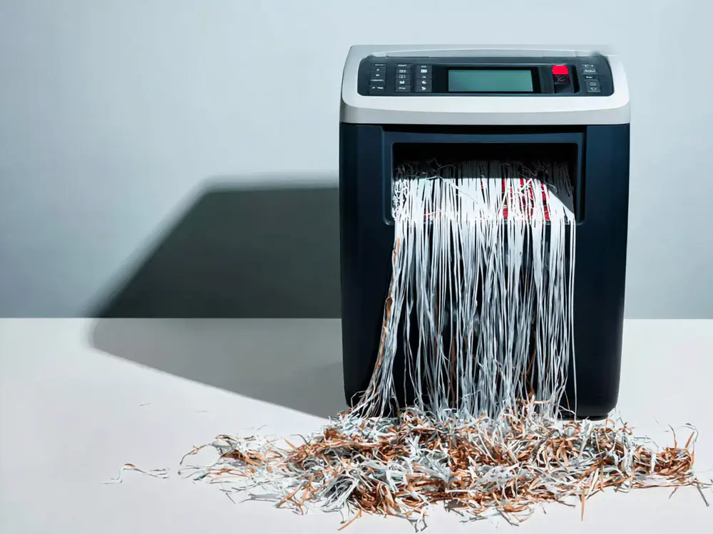 Ein Reißwolfgerät in Aktion, zerrissenes Papier kommt aus dem Gerät